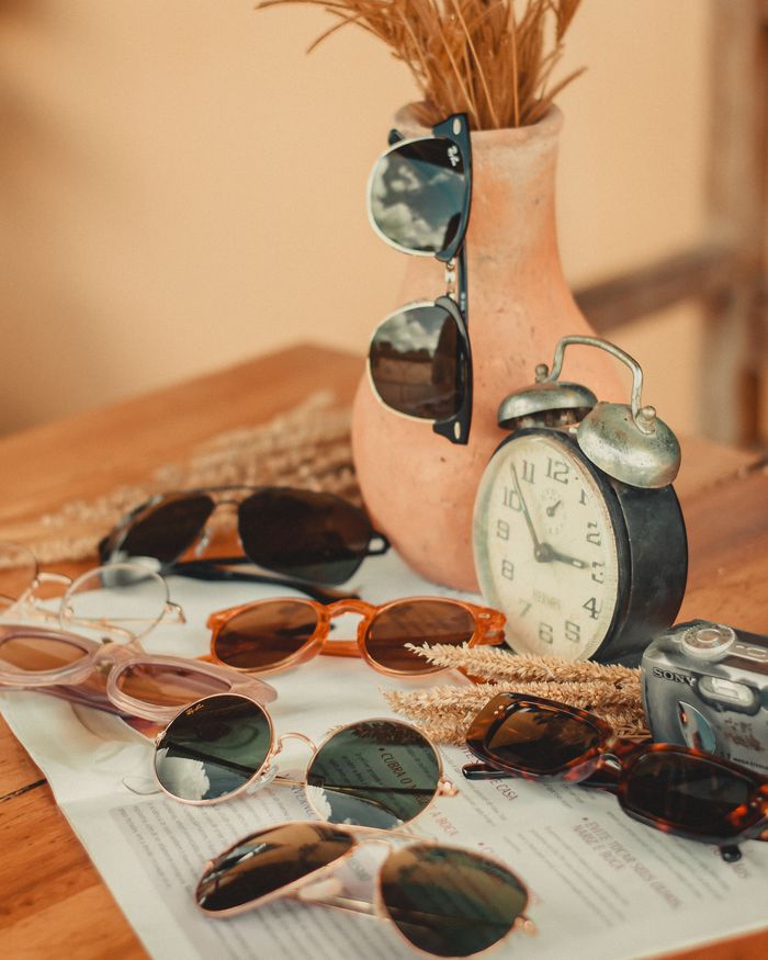 services-04 A collection of trendy sunglasses arranged with a vintage alarm clock for a stylish look.