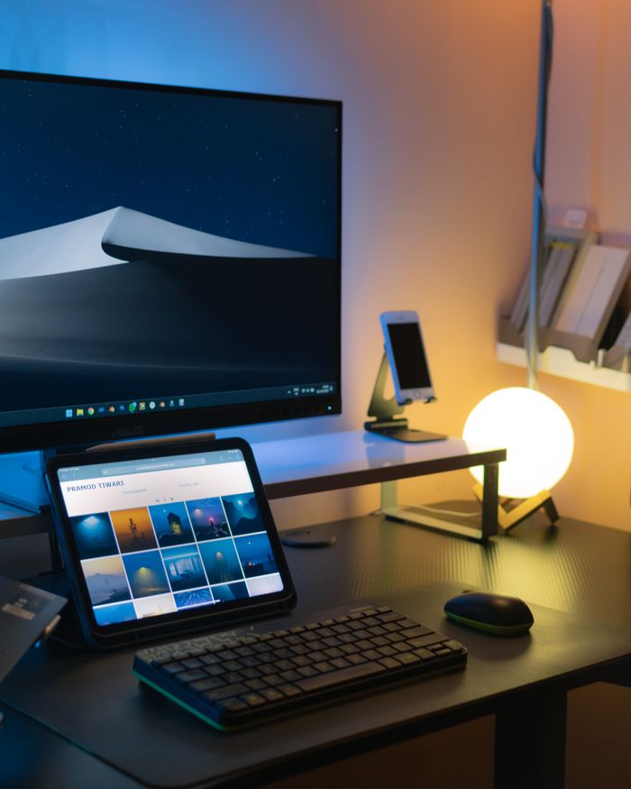 services-01 Sleek indoor workspace featuring computer, tablet, glowing desk lamp, and modern décor.