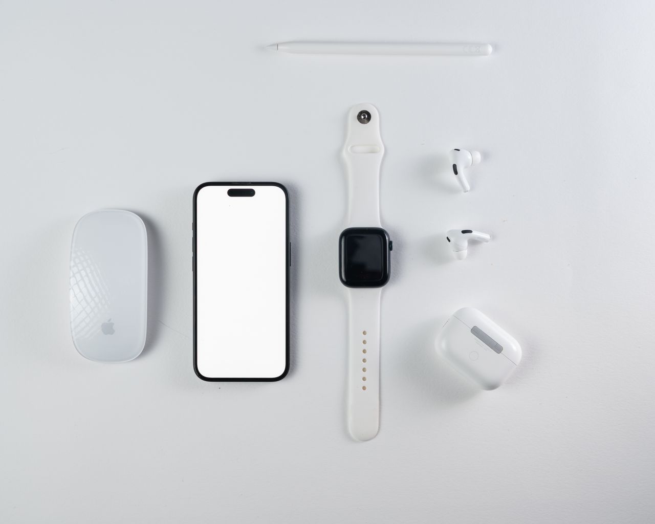 services-img Minimalist flat lay of smartphone, smartwatch, wireless earbuds, and mouse on a white background.