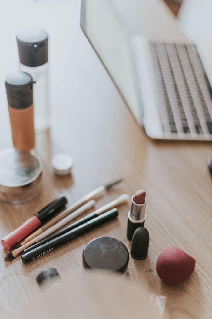 about-02 A collection of makeup items alongside a laptop on a wooden desk, ideal for beauty work settings.