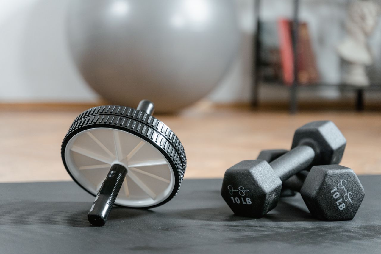 Mastering the First Impression: Your intriguing post title goes here Close-up of ab wheel and dumbbells on a mat in a home gym setting.